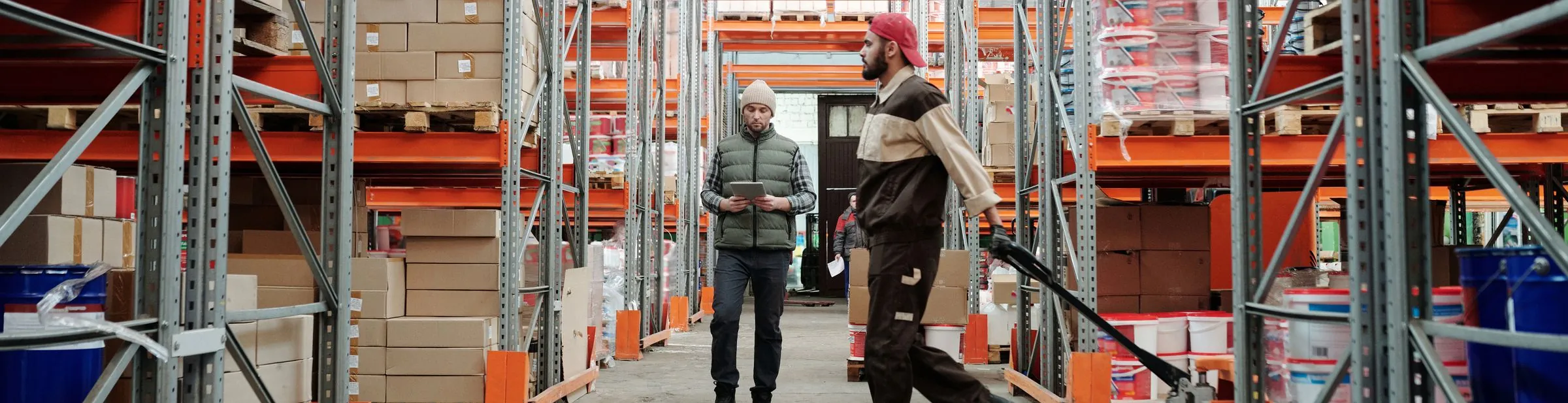 Two warehouse staff moving stock down an aisle
