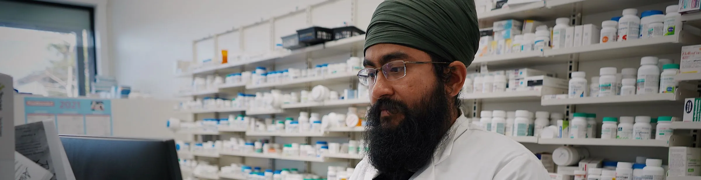 A pharmacist checking a bottle against the dispensary shelves