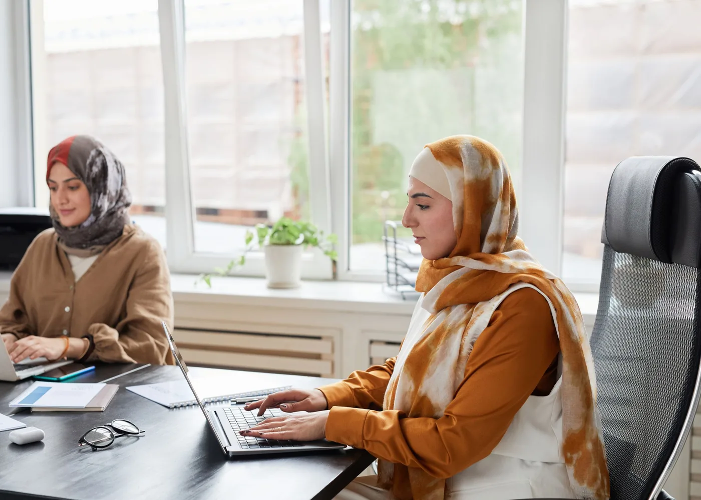 Two colleagues working through claims on their laptops