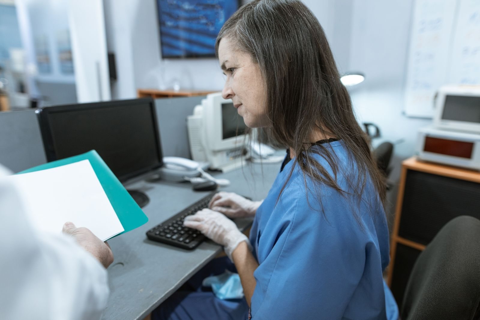Clinic administrator reviewing claim paperwork at a computer