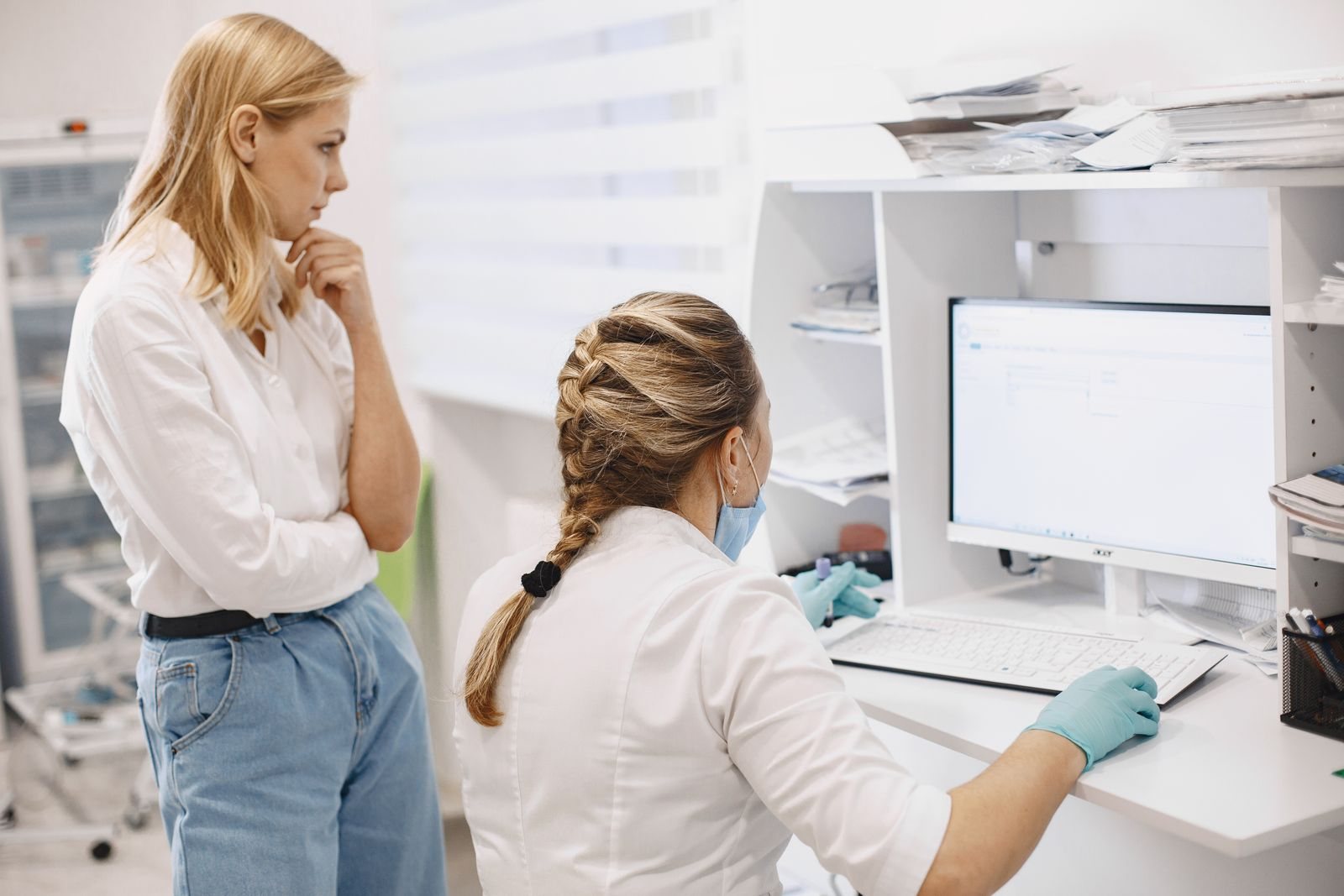 Two healthcare staff reviewing a patient record on a clinic computer