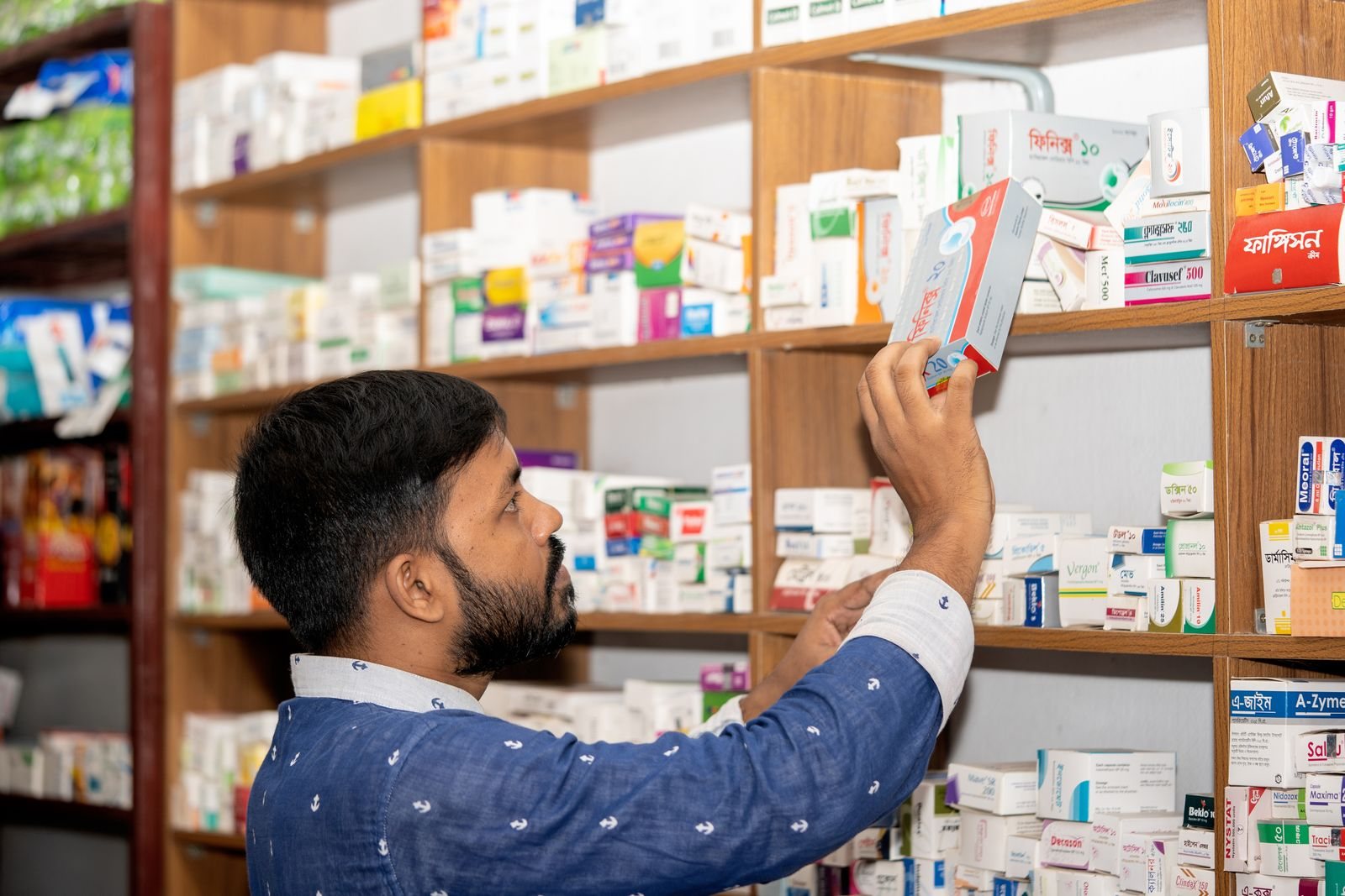 Pharmacist taking a medicine pack from a shelf